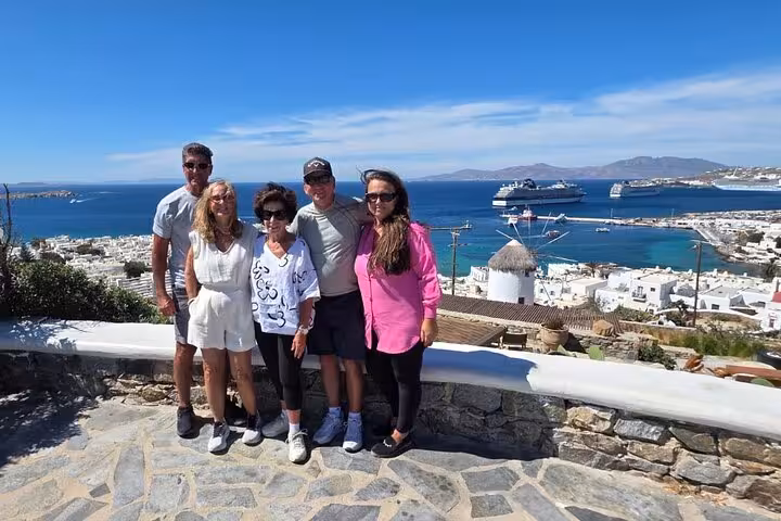 Travelers posing at Mykonos viewpoint overlooking Little Venice harbor and cruise ships on private half-day tour