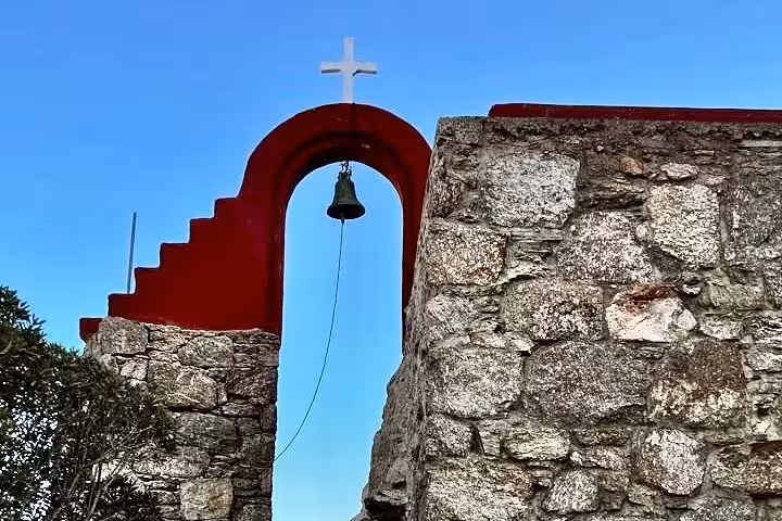 Red-arched church bell and stone wall in Mykonos, Greece, on a private custom island experience tour