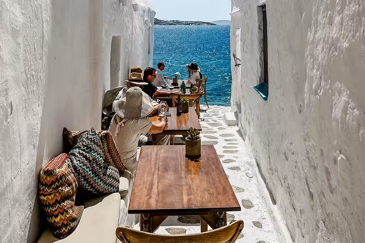 Seaside taverna alley in Mykonos with whitewashed walls and Aegean views, perfect stop on a private tour