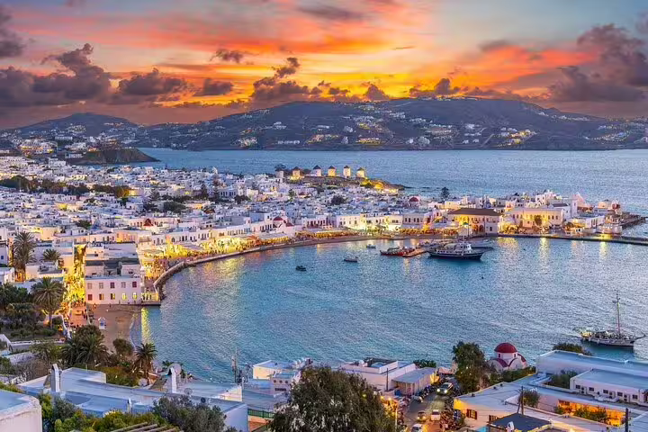 Breathtaking sunset over Mykonos harbor with iconic white buildings, perfect for a countryside tasting experience ride.