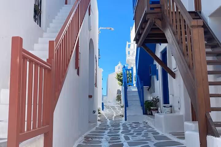 Charming Mykonos Town alley with whitewashed walls, stone path and stairs on a private walking tour experience