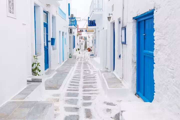Whitewashed alley with blue doors in Mykonos Town, a highlight of the From Athens day tour to Mykonos