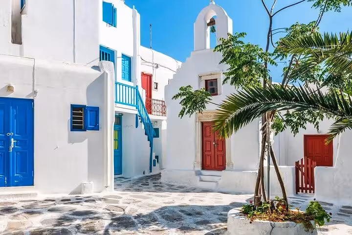 Whitewashed Mykonos alley with blue shutters and chapel, classic Cyclades stop on 7-day private tour from Athens