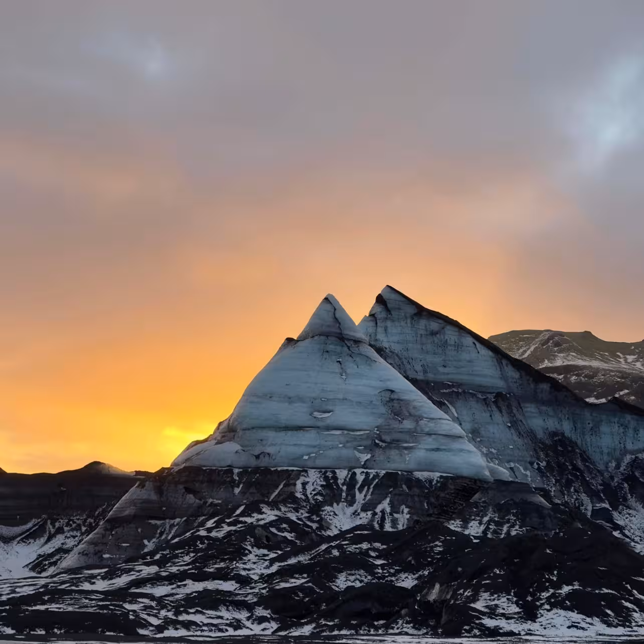 Dramatic sunset over Myrdalsjokull glacier ice peaks with volcanic black landscape on Katla ice cave tour from Vik