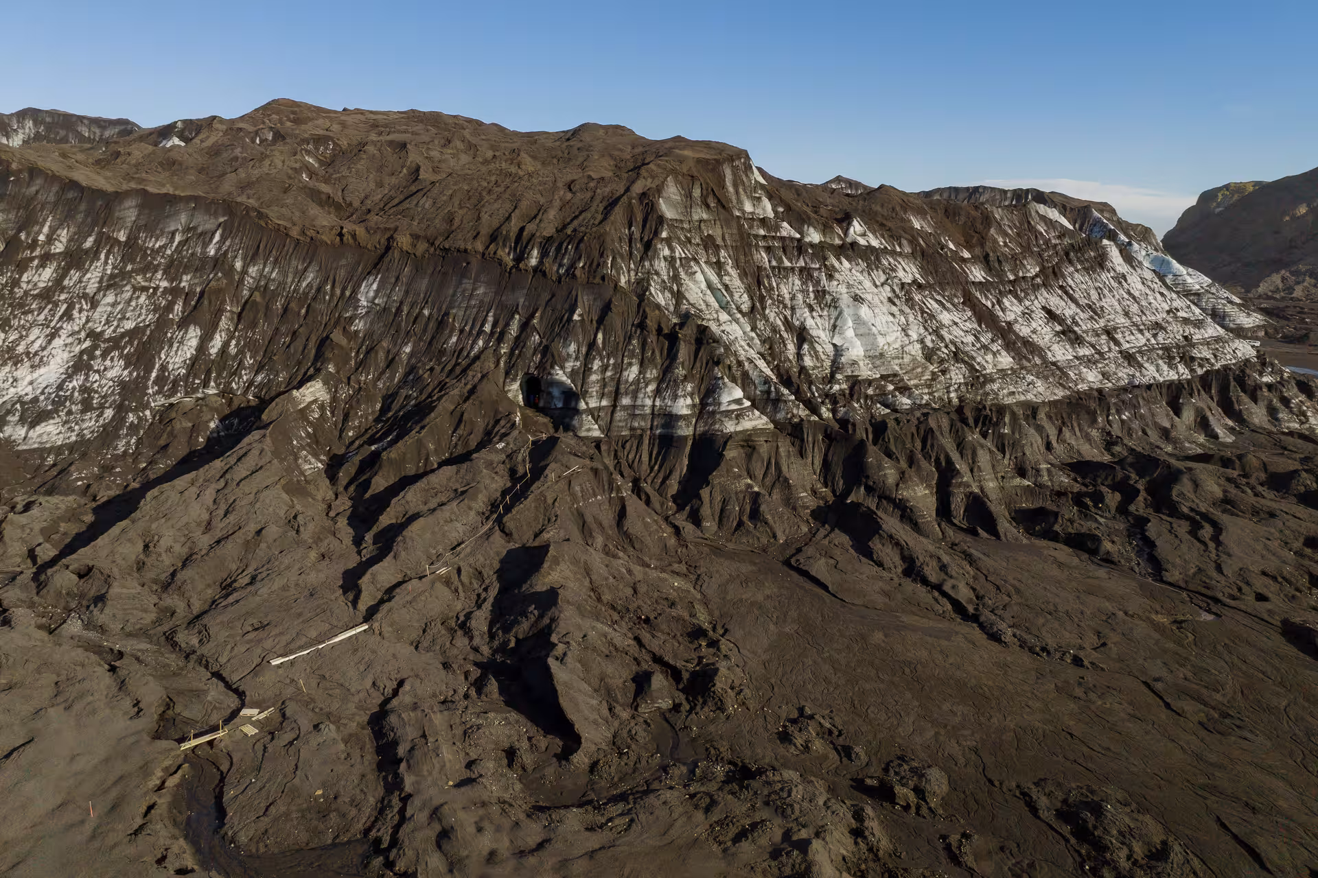Aerial view of Myrdalsjokull glacier with dark volcanic ash layers and white ice exposed on rugged terrain near Vik Iceland