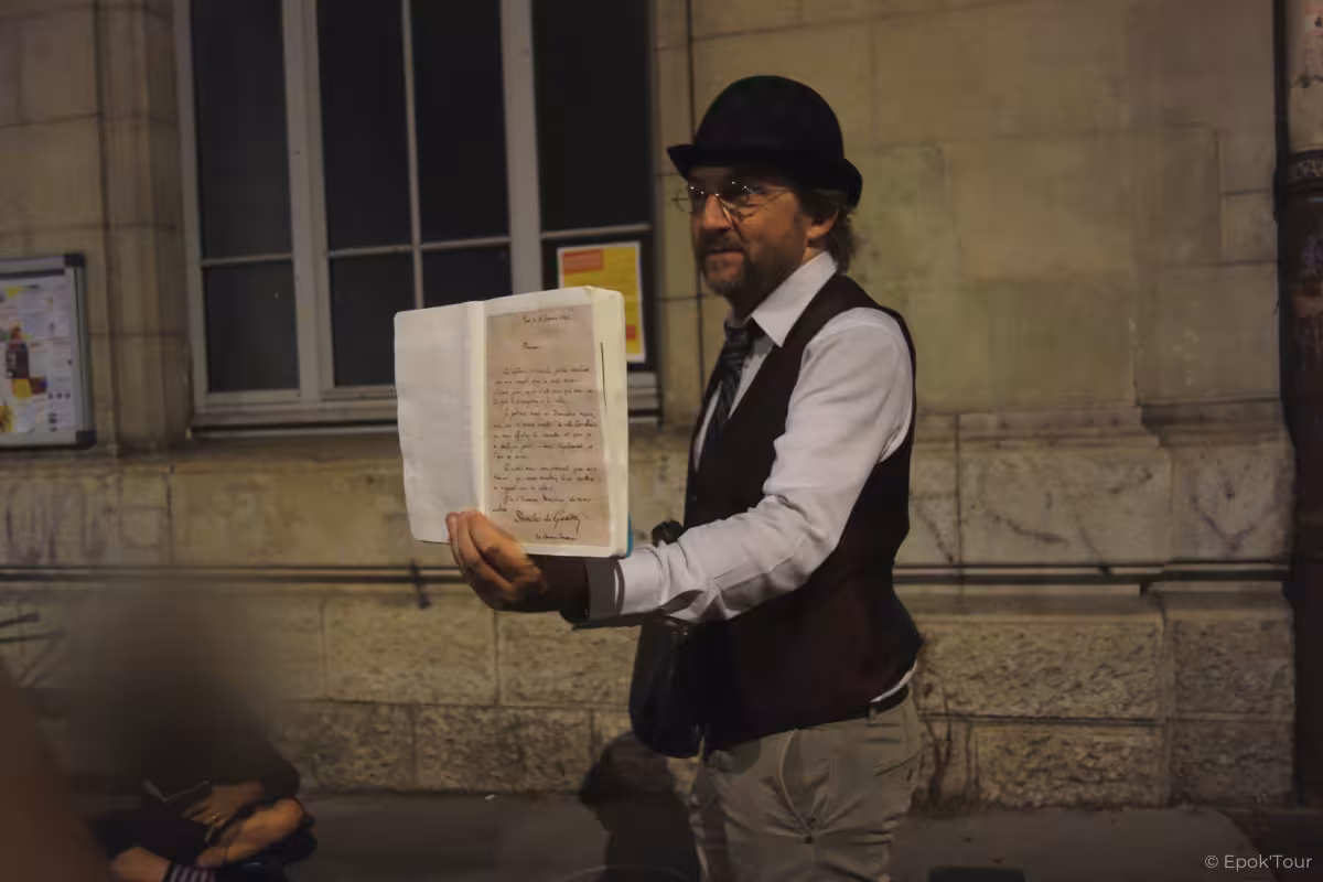 Tour guide in bowler hat holding handwritten letter during mystical Lyon walking tour at night