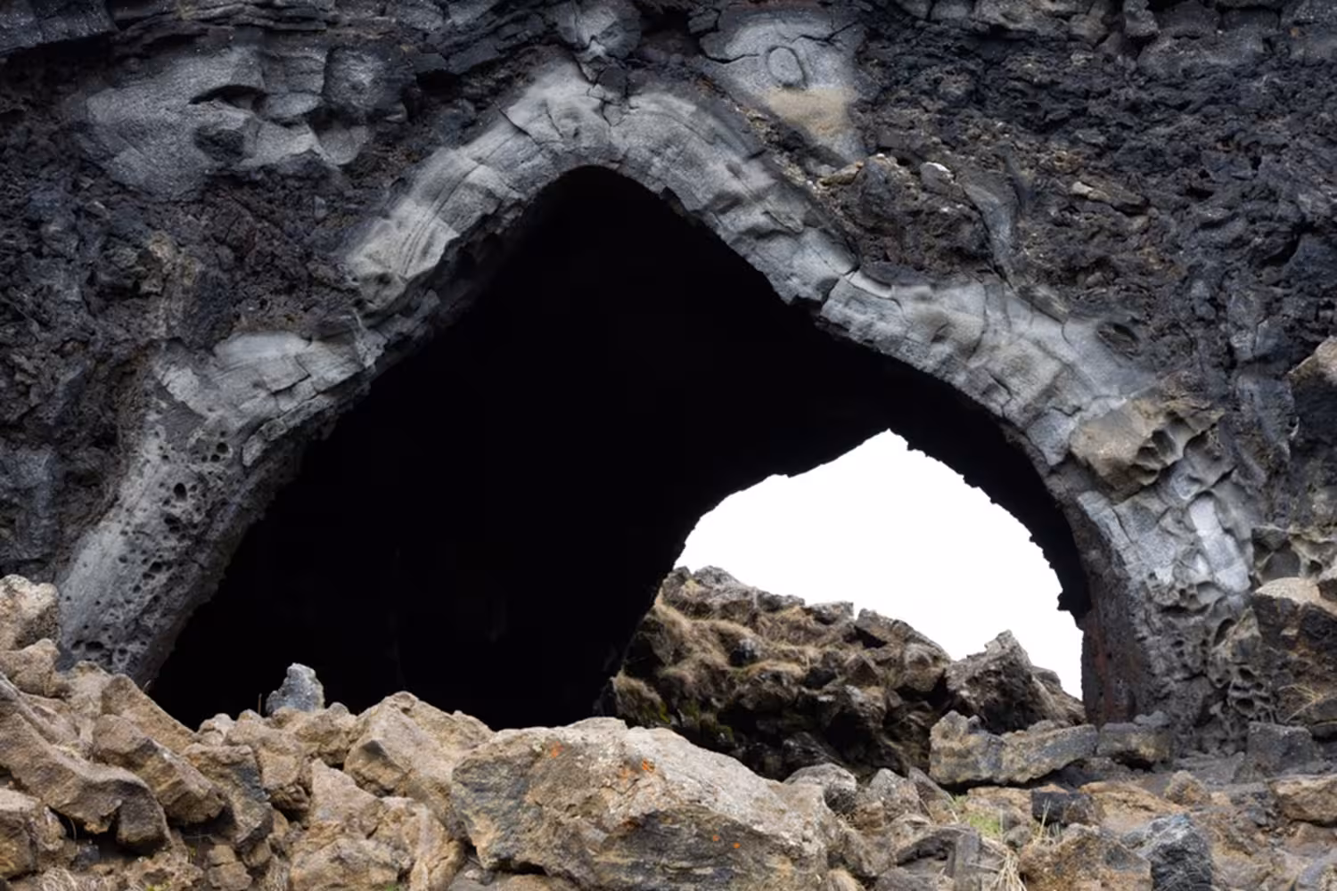 Dark volcanic lava cave arch opening at Lake Myvatn lava fields, Akureyri Iceland