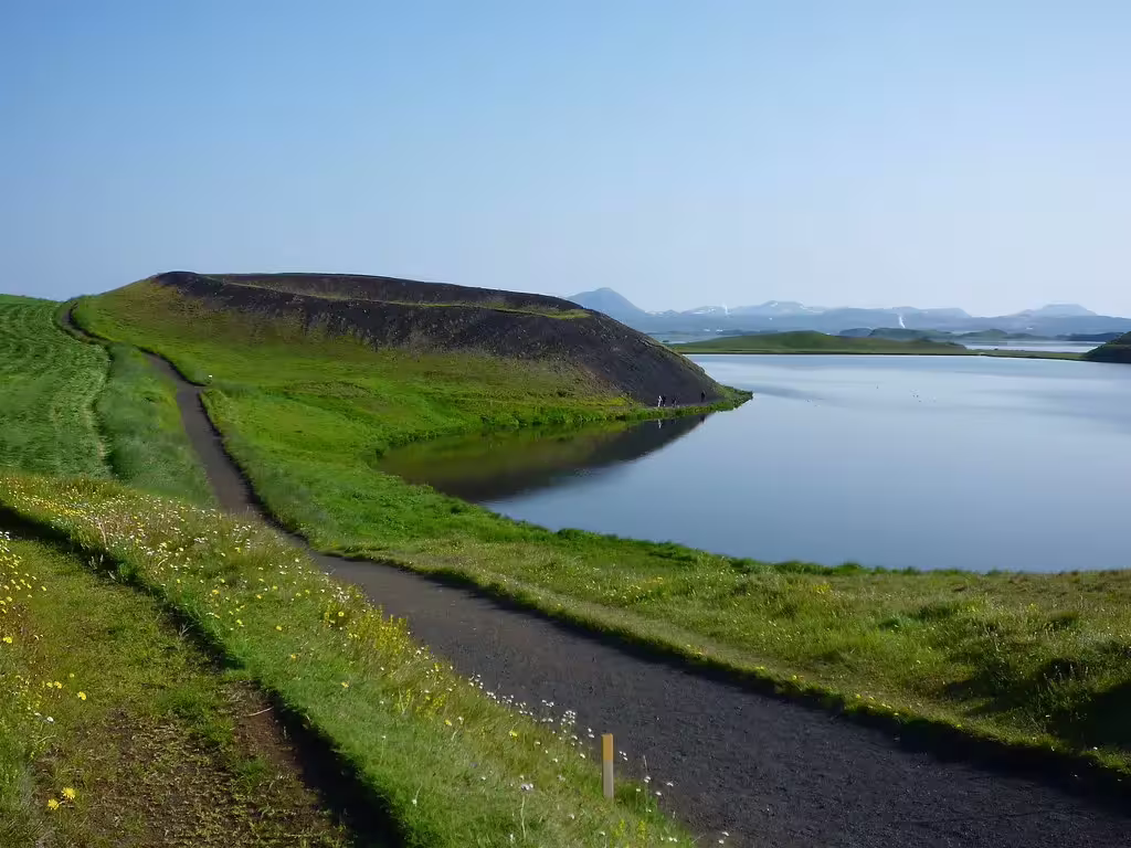 Scenic path along Lake Mývatn with volcanic pseudo-craters and calm reflective water near Akureyri, Iceland