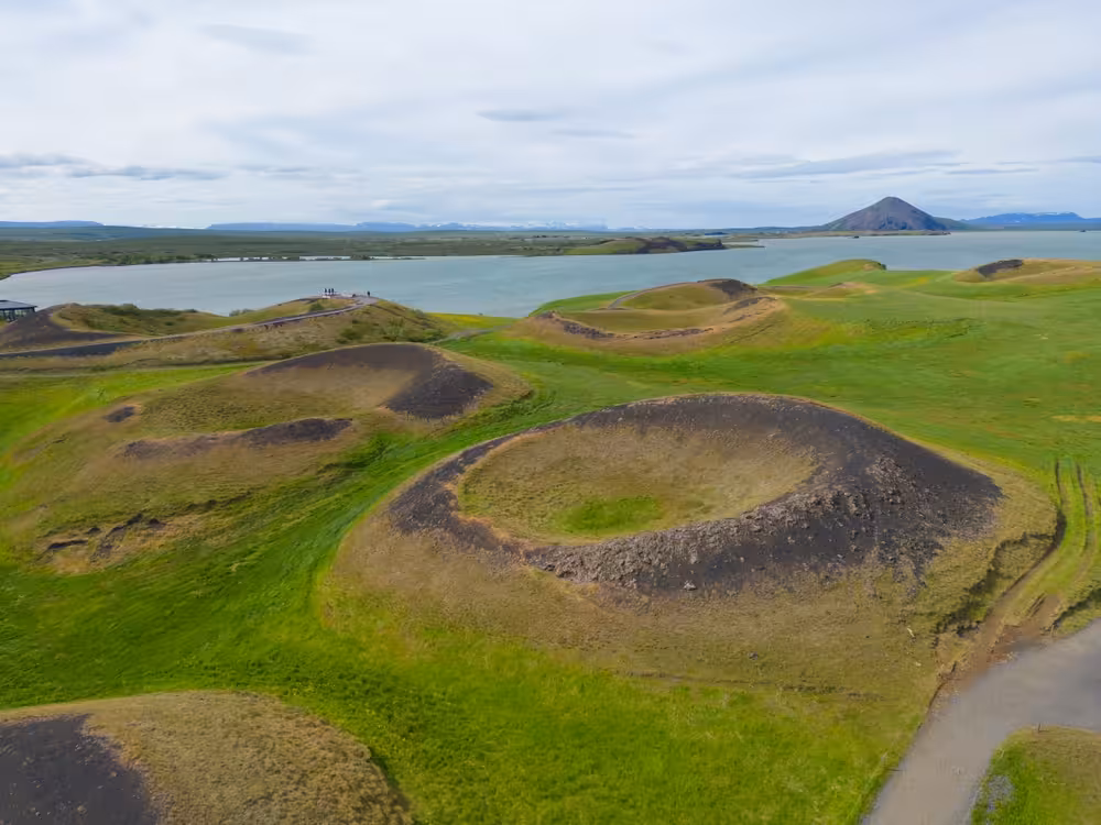 Aerial view of volcanic pseudo-craters at Lake Myvatn, Iceland, with green grass and volcanic mountain backdrop
