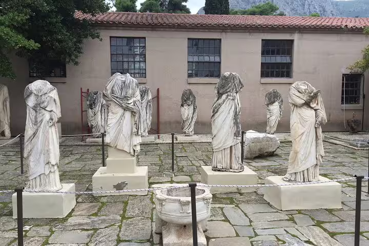Ancient marble statues in a Greek archaeological museum courtyard, visited on the Nafplio wine tasting tour via Corinth Canal