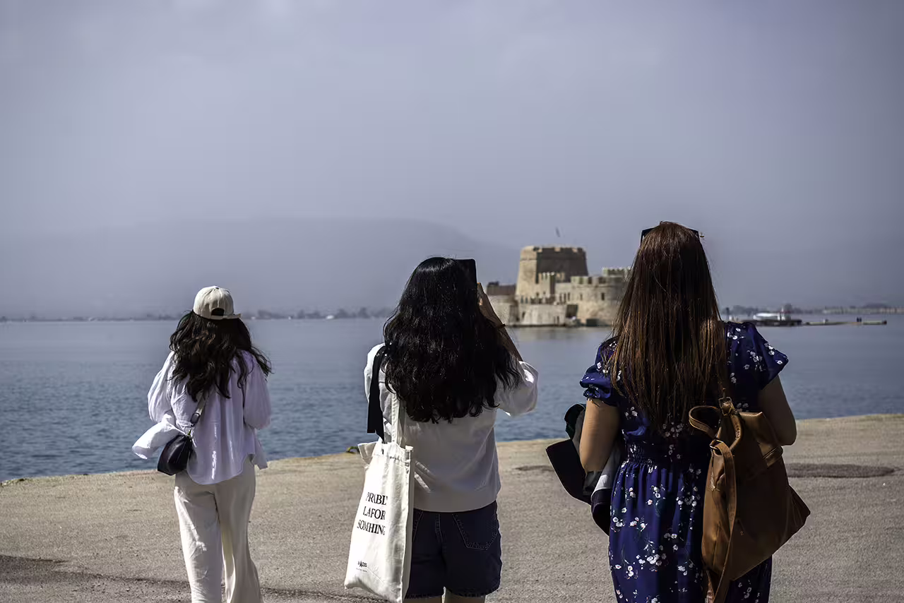 Travelers viewing Nafplion Bourtzi Castle by the sea on an Ancient Corinth and Nafplion guided day trip