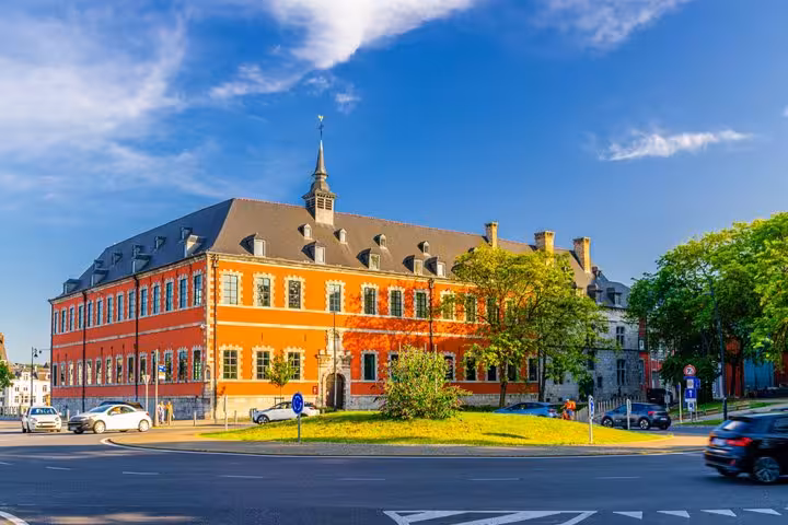Historic orange baroque building on a roundabout in Namur, Belgium, under a blue sky