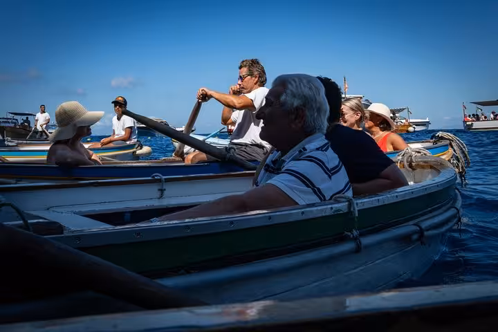 A group enjoys a boat ride under clear skies to the Blue Grotto, a highlight of the Naples guided tour.