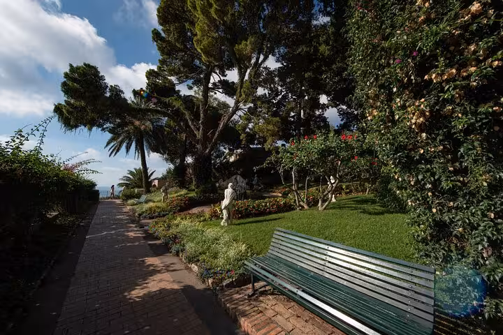 Lush garden pathway with benches and statues, ideal for a scenic stroll on the Naples Blue Grotto and Faraglioni tour.