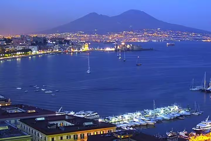 Evening Naples city tour view of Marina and Bay of Naples with Mount Vesuvius and Castel dell’Ovo lights reflecting on water