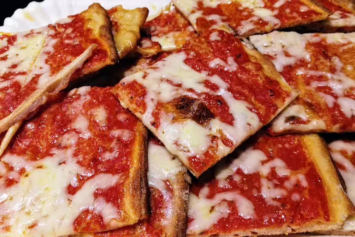 Freshly baked Neapolitan pizza al taglio slices loaded with melted mozzarella and rich tomato sauce on Naples street food walking tour