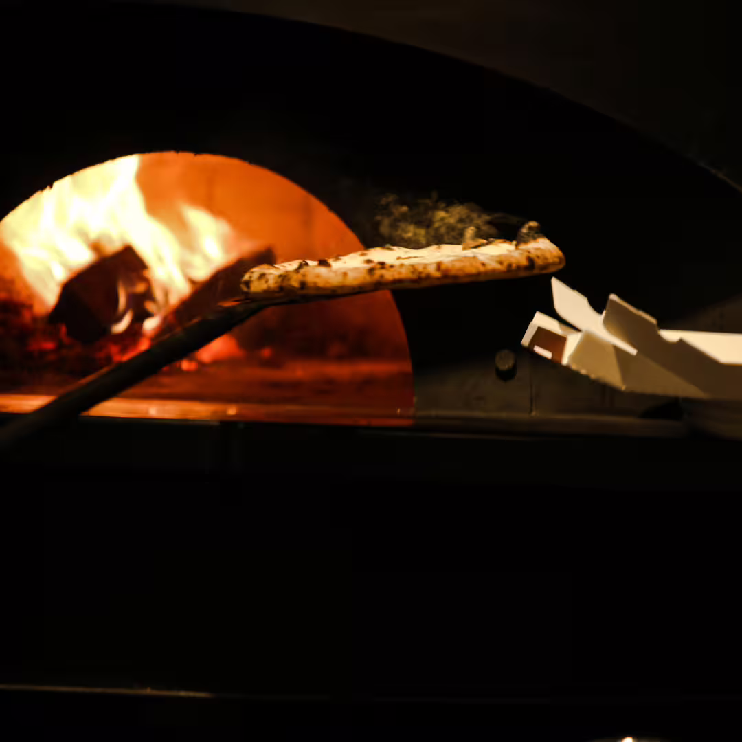 Wood-fired oven baking authentic Neapolitan pizza on peel during immersive Naples pizza master class experience