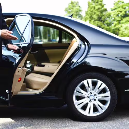 Private chauffeur opening luxury sedan door for Naples to Pompeii transfer, showcasing comfortable, premium car service in Italy