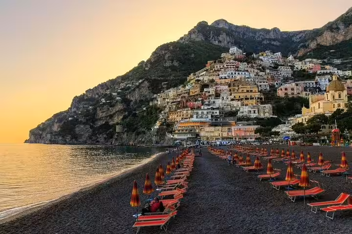 Sunset at Positano beach with umbrellas and hillside houses on private tour from Naples to Pompeii, Sorrento and Amalfi