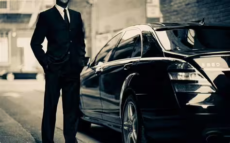 Professional driver in suit stands beside premium black car ready for Naples to Pozzuoli private transfer with door-to-door service
