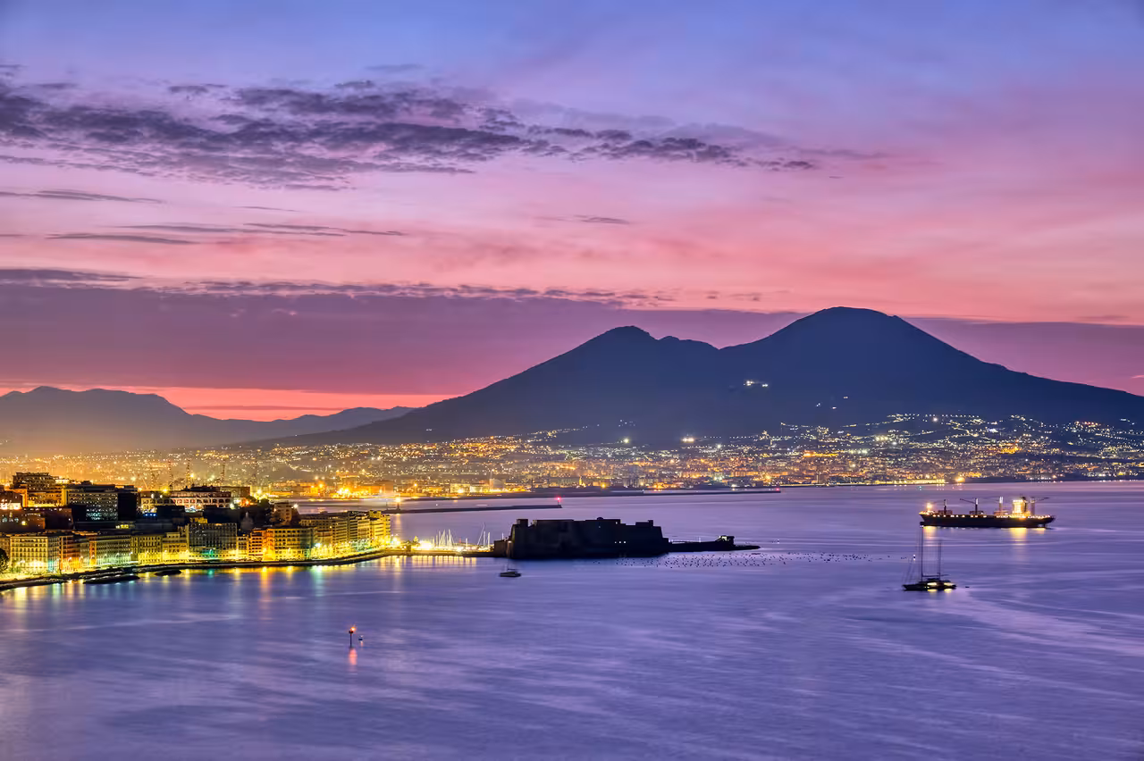 Naples waterfront at dusk with Mount Vesuvius, perfect backdrop for a Gulf of Naples sailing ship dinner show