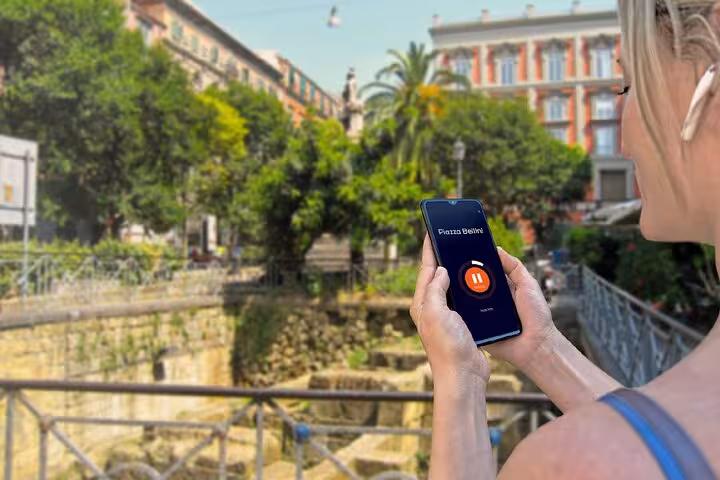 Tourist holding smartphone with Piazza Bellini audio guide app during Naples self-guided walking tour