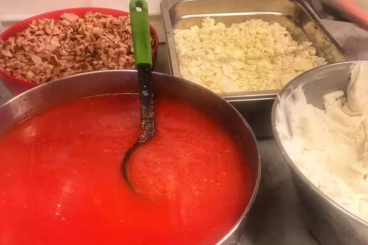 Fresh tomato sauce, mozzarella, and meat toppings prepared at a Naples street food market kitchen stop