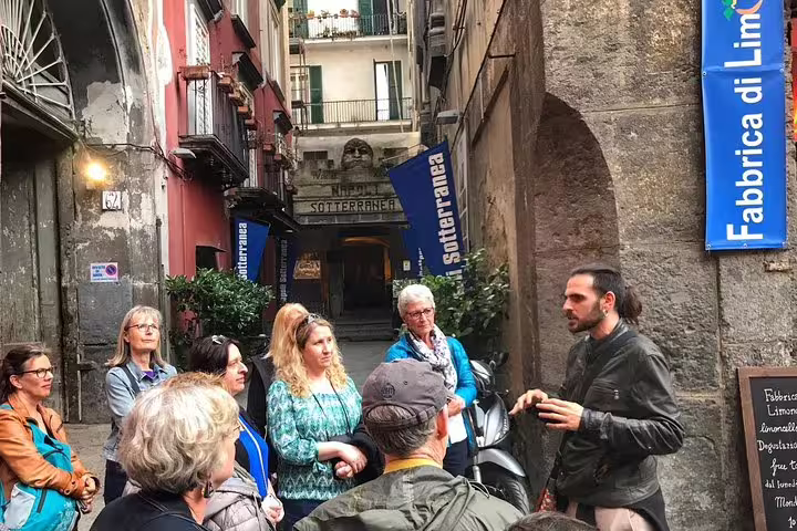 Local guide leading a Naples street food walking tour group through historic city center alleyways
