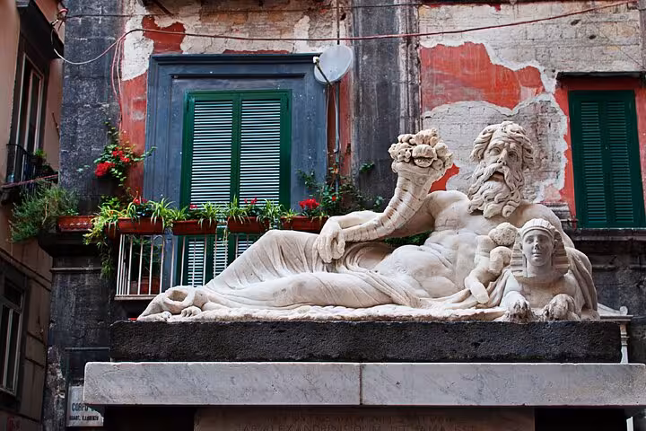 Ancient reclining marble statue with sphinx on a pedestal in Naples historic city center