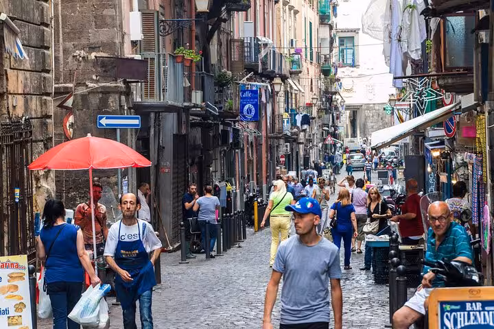 Vibrant street scene in Naples showcasing bustling local life on a cobblestone alley, ideal for walking tour exploration.