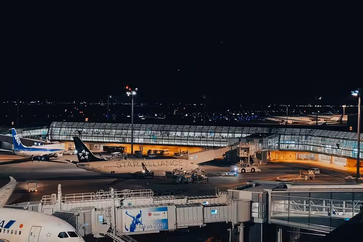Night view of Narita Airport with parked airplanes, highlighting convenient private transfer services to Tokyo hotels.
