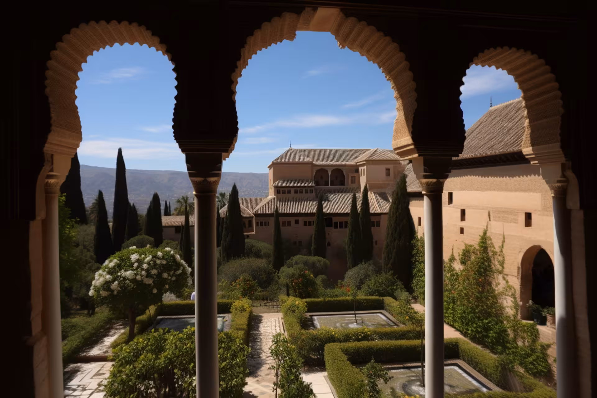 Elegant arches framing lush gardens and historic architecture in the Nasrid Palaces at the Alhambra.