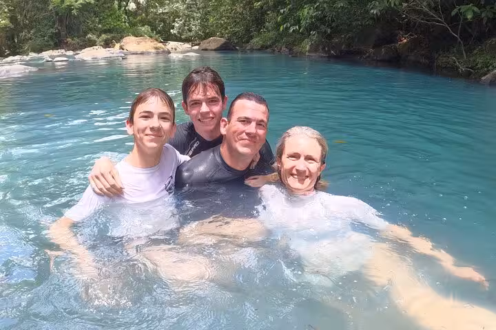 A family enjoying the refreshing waters of the Río Celeste natural pool in Costa Rica.