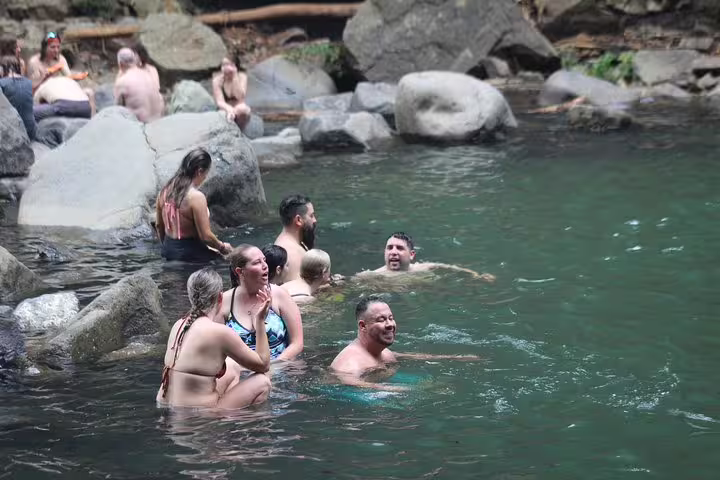 Visitors relaxing in the natural pool under Nauyaca Waterfalls, a highlight of the hiking or 4x4 ride tour experience.