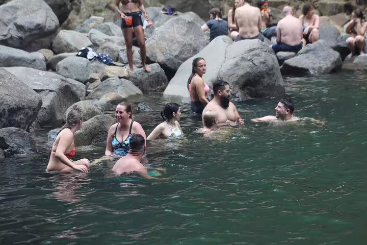 Tourists swimming and socializing in the scenic waters of Nauyaca Waterfalls, part of an adventurous tour in Costa Rica.