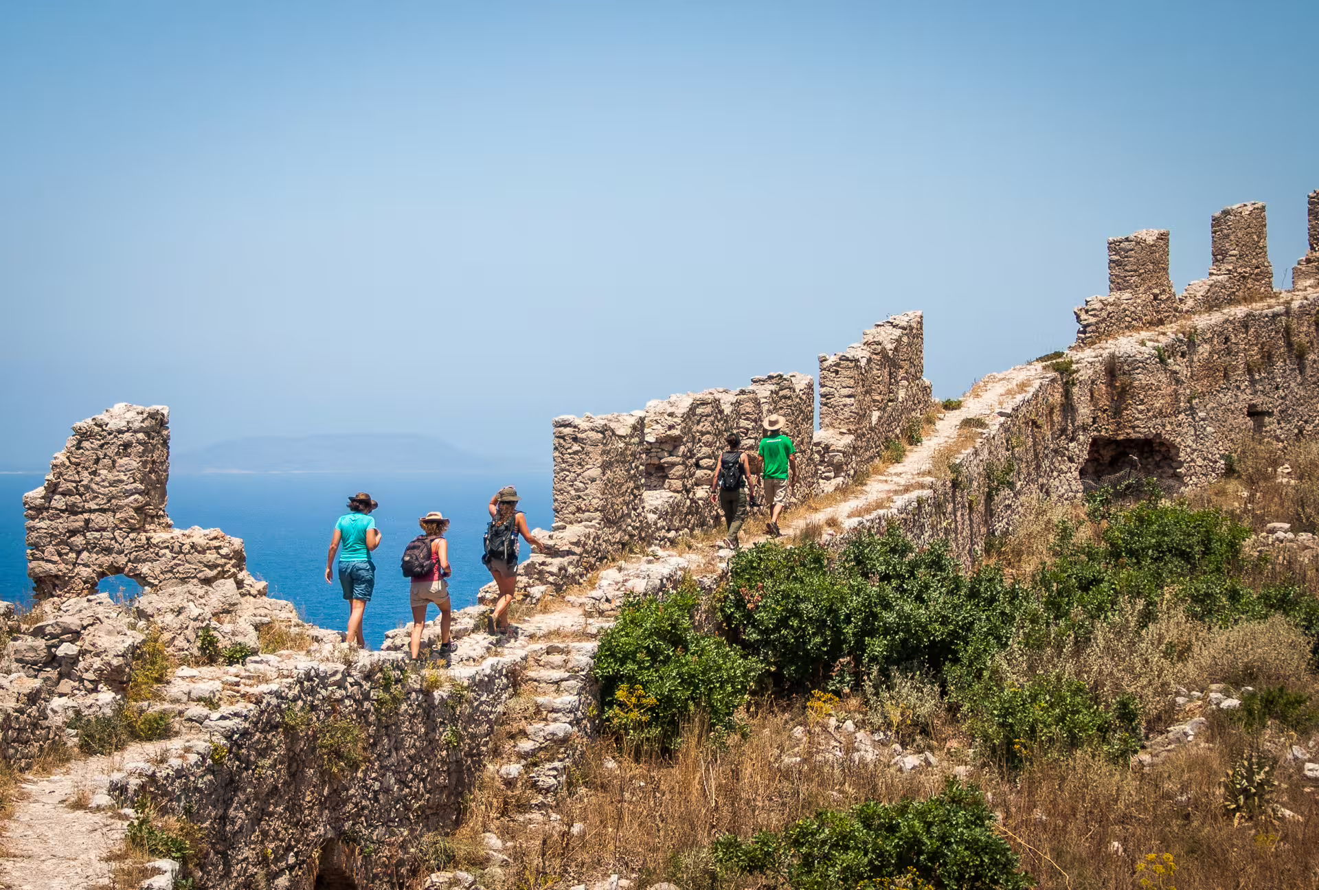 Hikers explore cliffside stone fortress walls above the sea on the Navarino Bay hiking tour near Pylos, Greece