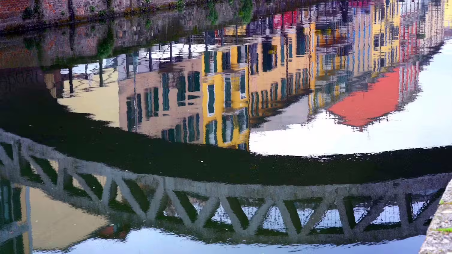 Colorful Navigli canal houses and iron bridge reflected in the water on a Milan photography stop during a guided walking tour