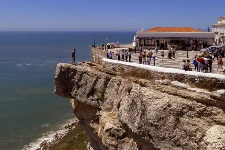 Scenic view of Nazaré's cliffside promenade overlooking the Atlantic Ocean with visitors enjoying the panorama.
