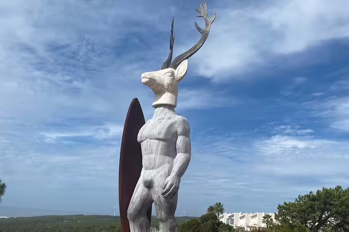 Unique sculpture of a humanoid deer with antlers and surfboard in Nazaré, highlighting artistic attractions on the tour.