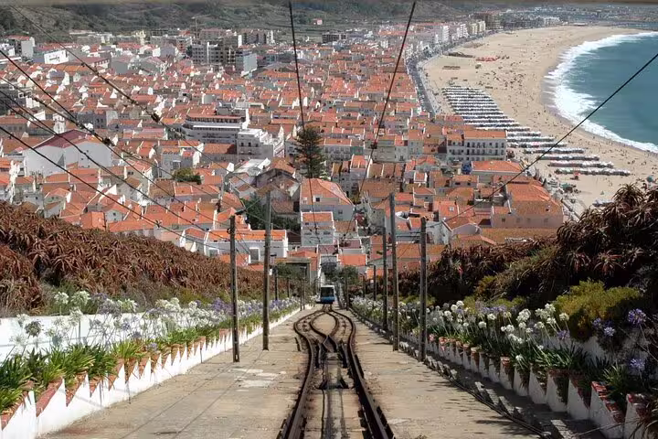 Scenic view of Nazaré with its iconic funicular railway, vibrant rooftops, and sandy beach, featured in a private tour from Lisbon.