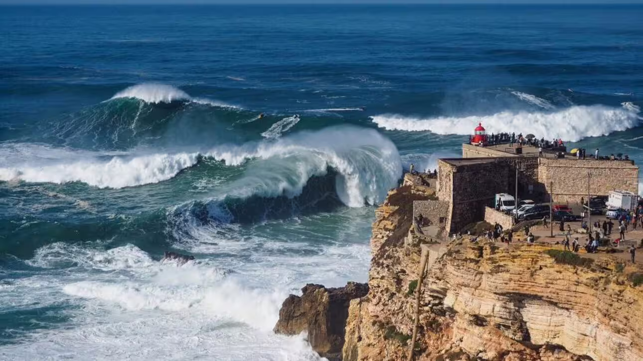 Spectacular waves crashing at Nazaré's lighthouse, a must-see on the Lisbon to Nazaré guided tour.