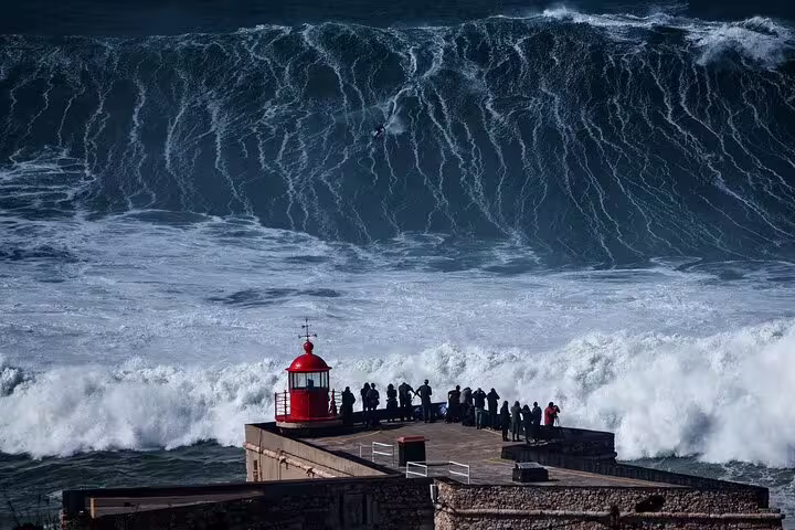 Tourists watch massive waves at Nazare lighthouse, famous for big wave surfing, on a scenic half-day tour from Obidos.