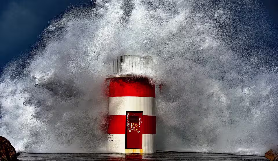 Dramatic waves crash against a red and white lighthouse in Nazaré, capturing Portugal's rugged coastal beauty.