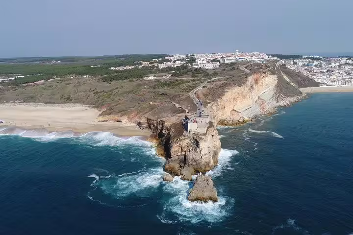 Scenic coastal view of Nazareth, Portugal, featuring dramatic cliffs and ocean waves, ideal for a cultural and historical private tour of Fatima, Nazareth, and Óbidos.