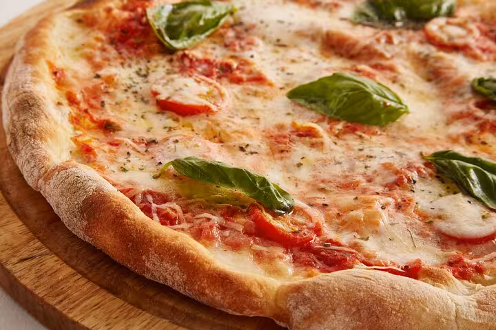 Freshly baked Neapolitan pizza with basil leaves on a wooden board, perfect for a hands-on cooking class in Naples.