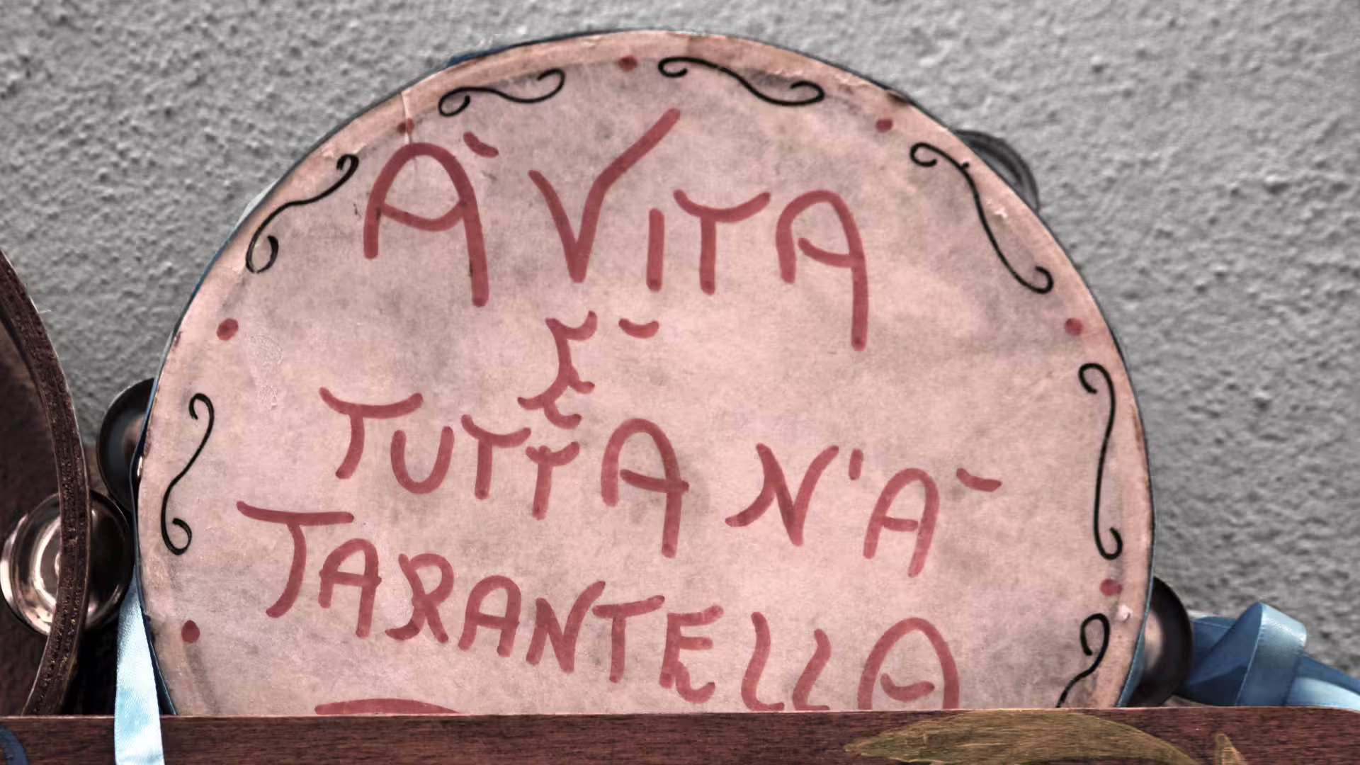 Tamburello artigianale con scritta dialettale A vita è tutta n’a tarantella, souvenir tipico nel cuore storico di Napoli