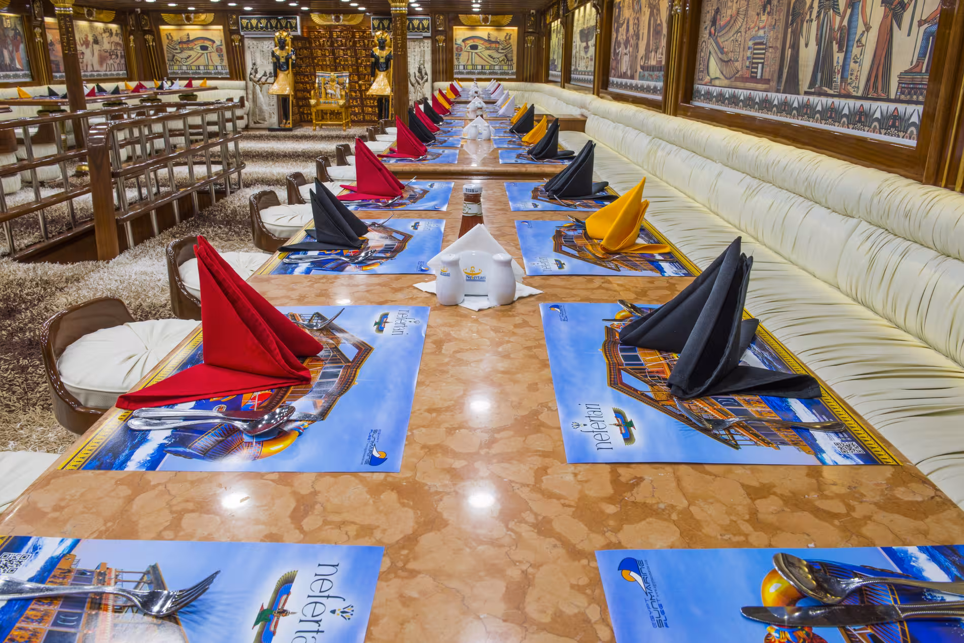 Egyptian-themed dining room with colorful folded napkins on marble tables aboard Nefertari glass bottom boat
