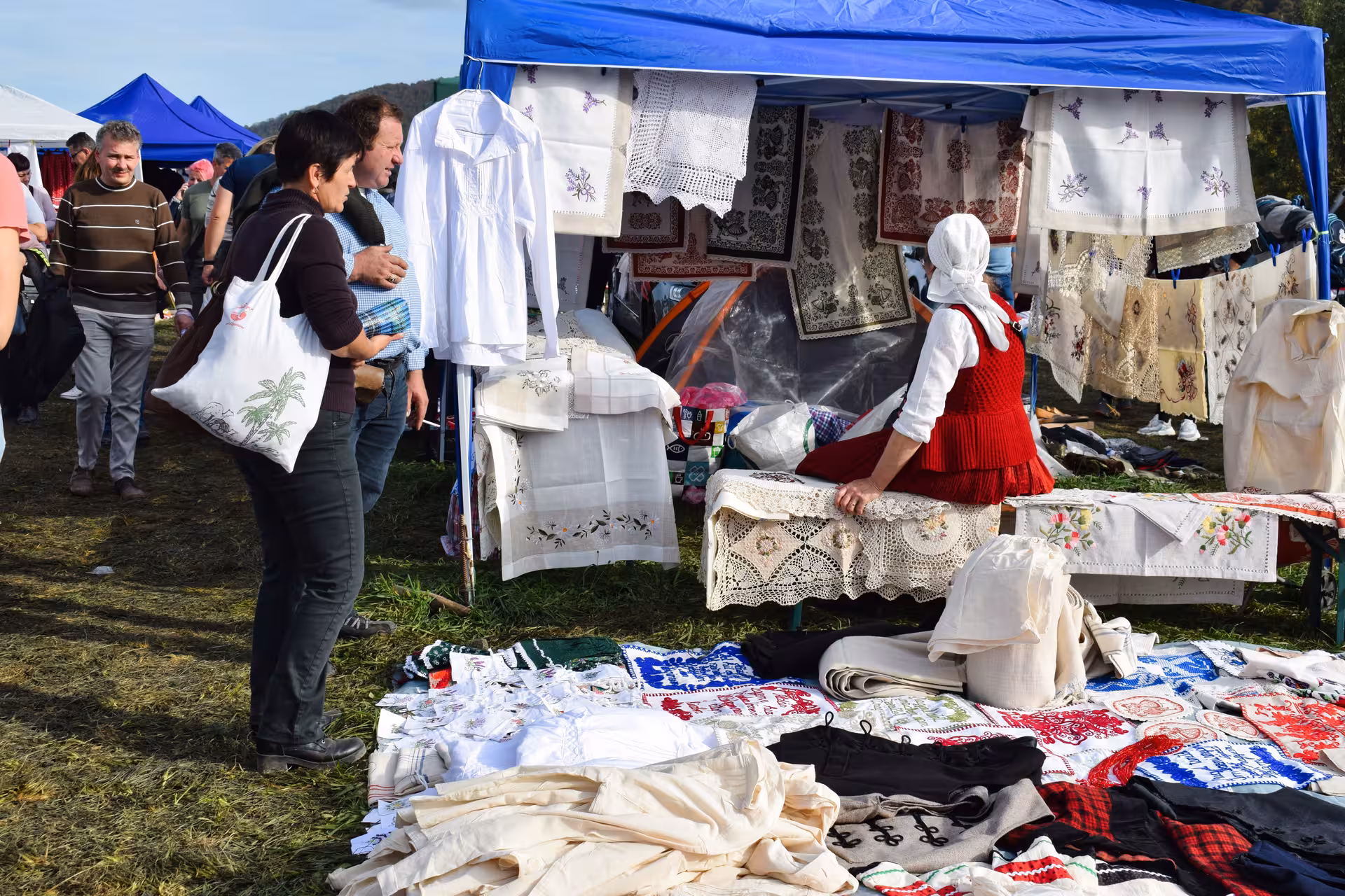Vendor selling traditional Romanian embroidered textiles and lace at the vibrant Negreni Flea Market antiques tour