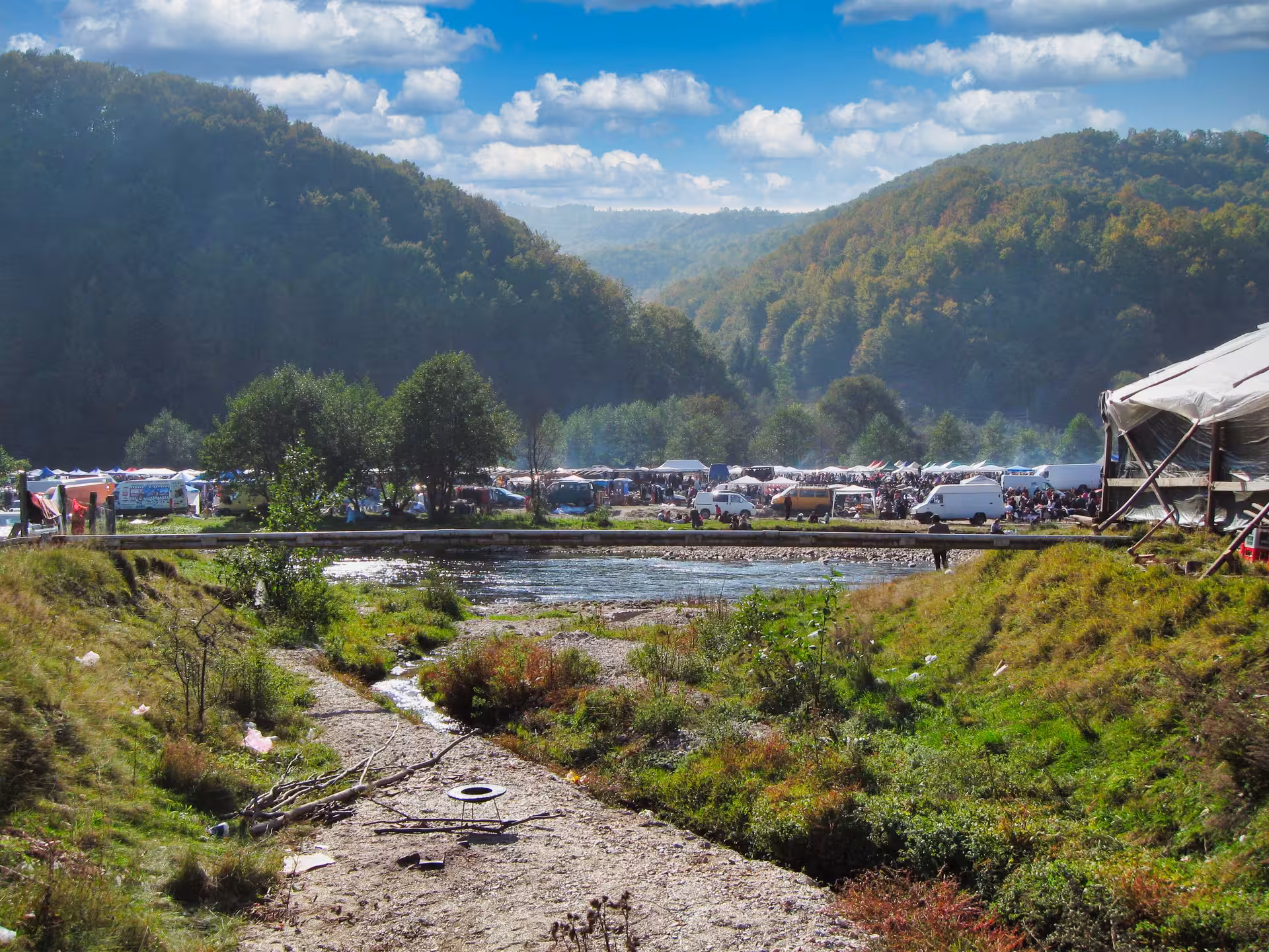 Scenic panoramic view of Negreni Flea Market nestled in lush Romanian hills beside a flowing river
