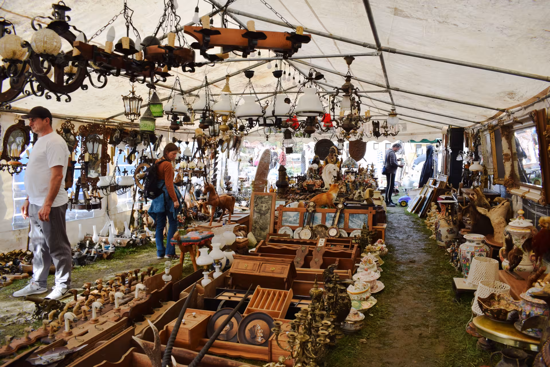 Visitors browsing vintage chandeliers and antique collectibles under a tent at Negreni Flea Market guided tour